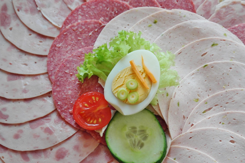 Cold meat platter with various types of sausage, boiled egg, cucumber, tomato and lettuce as a typical German breakfast.
