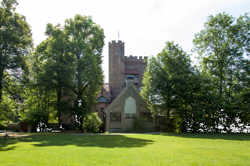 Historisches Gebäude in einer grünen Parkanlage nahe München, umgeben von Bäumen und Wiese, Standort des Sommercamps in München Kastell.