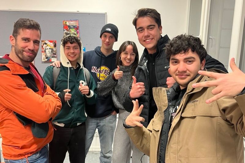 Jóvenes internacionales en un curso de alemán en Colonia posan juntos y muestran el pulgar hacia arriba.