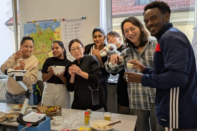 International language students stand together in a language school in Regensburg, enjoying a break.